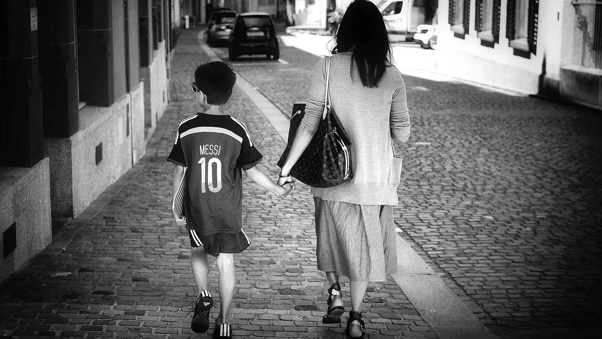 A young fan in a Messi number 10 Argentina shirt walking down a street holding an adult's hand